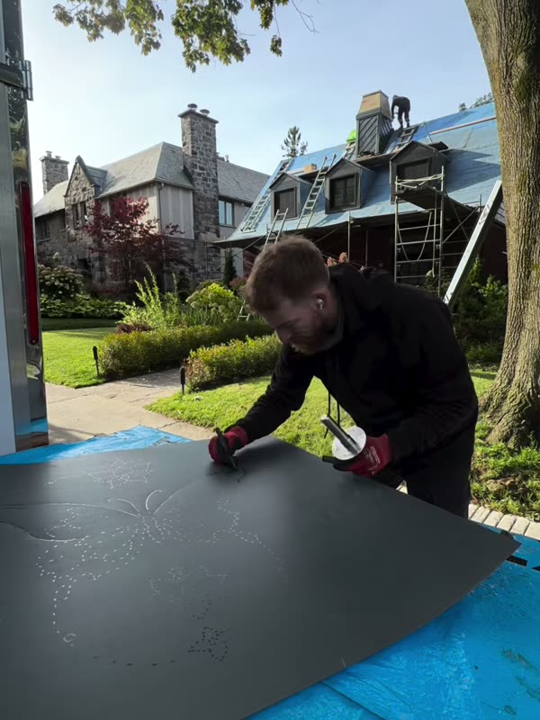 Laying out a metal sheet in front of a stone heritage house